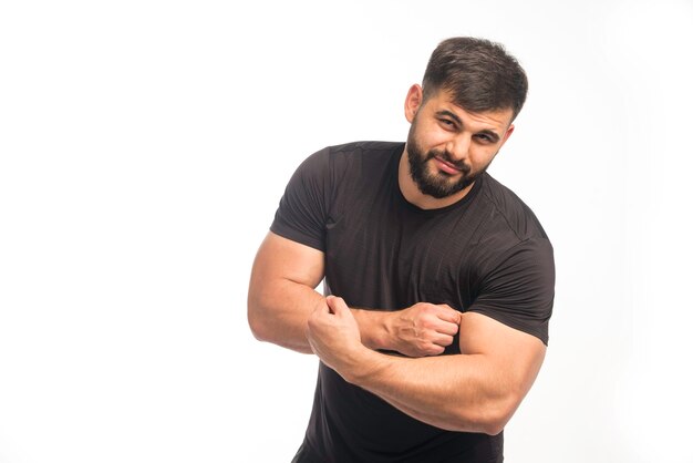 Sportieve man in zwart shirt met zijn biceps.