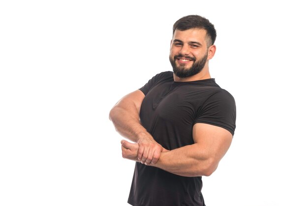 Sportieve man in zwart shirt zijn hand op zijn armspieren te zetten