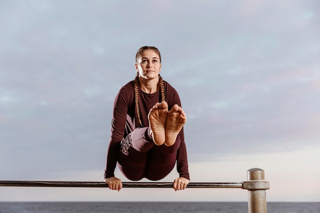 Gratis foto sportieve vrouw aan het strand die geschiktheidsoefeningen doet