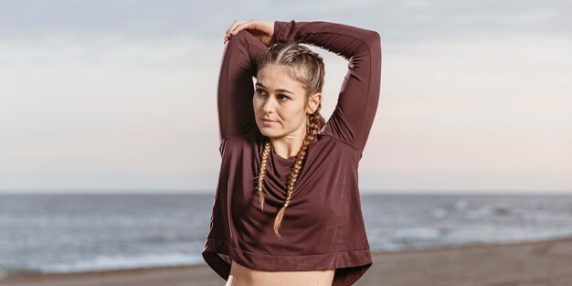 Sportieve vrouw aan het strand poseren tijdens het strekken