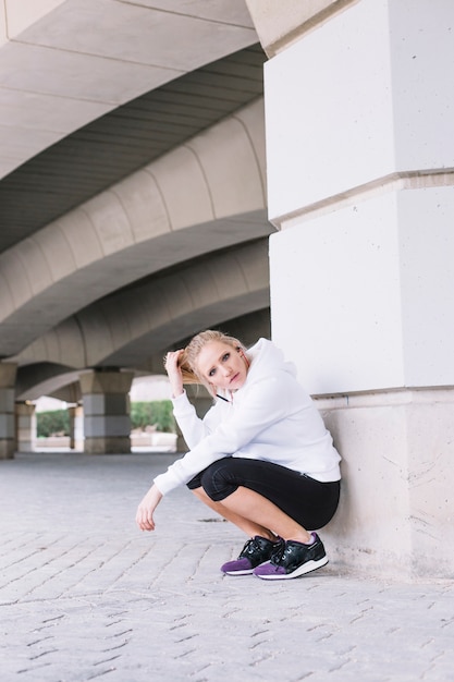 Sportieve vrouw dichtbij pijler die camera bekijkt