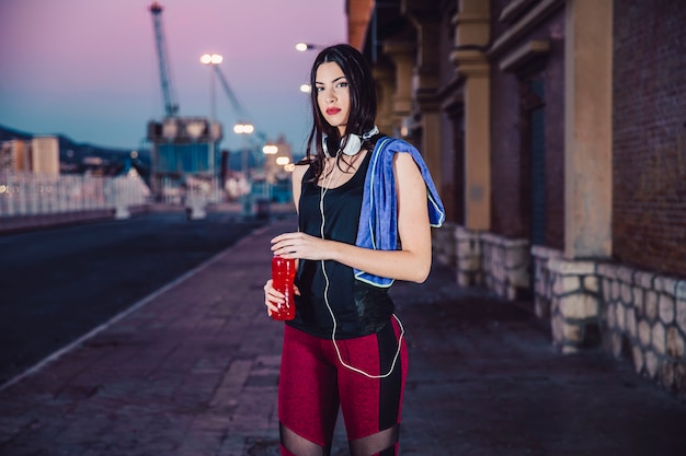 Sportieve vrouw die met fles camera bekijkt