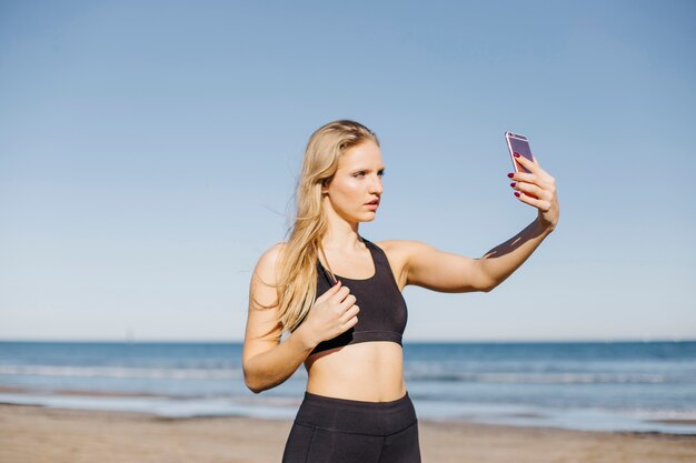 Sportieve vrouw die selfie op het strand