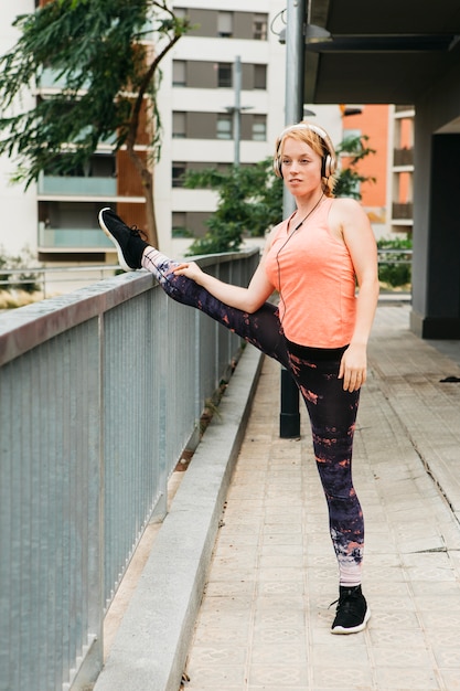 Sportieve vrouw die zich uitstrekt in de stedelijke omgeving