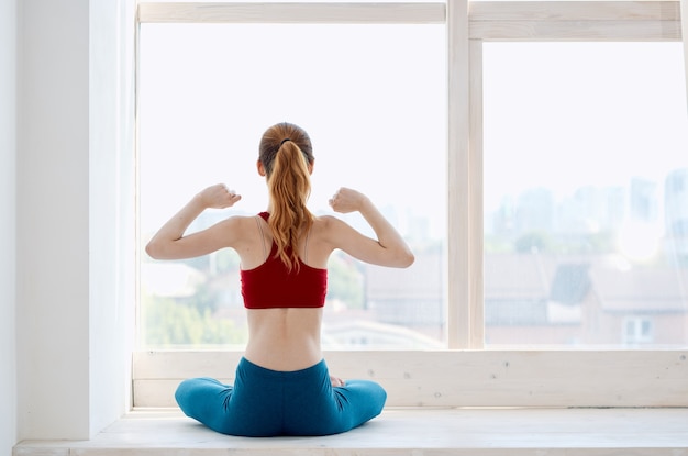 Sportieve vrouw doet yoga oefening asana in de buurt van het raam. hoge kwaliteit foto Premium Foto