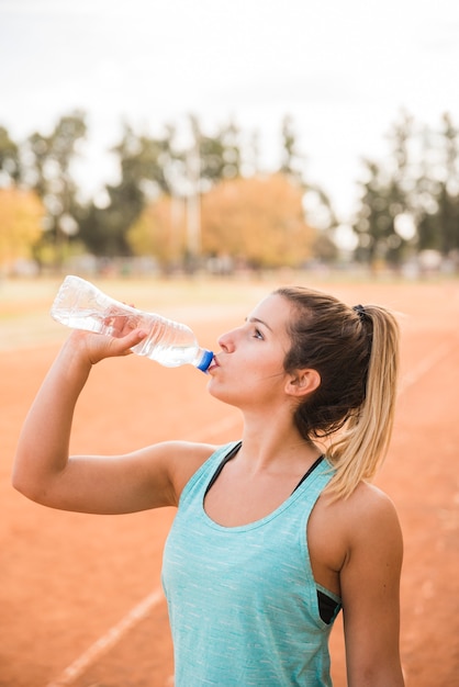 Gratis foto sportieve vrouw drinken op stadion bijhouden