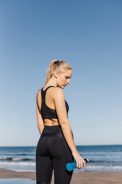 Sportieve vrouw met plastic fles op het strand