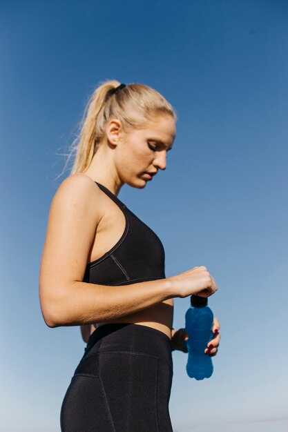 Sportieve vrouw met plastic fles op het strand