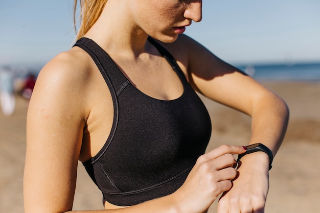 Gratis foto sportieve vrouw met smartwatch op het strand