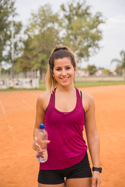 Sportieve vrouw met waterfles op stadionspoor