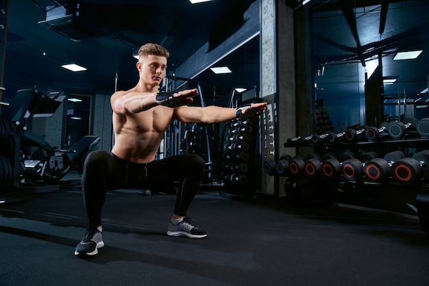 Sportman die hurkzit in gymnastiek doen.