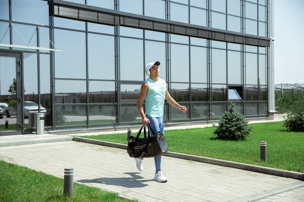 Sportman loopt tegen modern glazen gebouw, luchthaven in megapolis in de zomerdag.