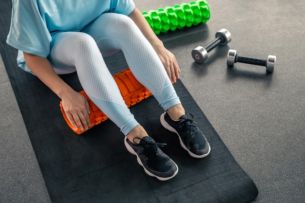 Gratis foto sportvrouw met schuimroller voor spieren en fascia die voet strekt