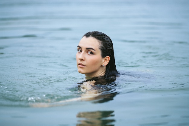 Sportvrouw zwemmen in het meer in zwarte zwembroek