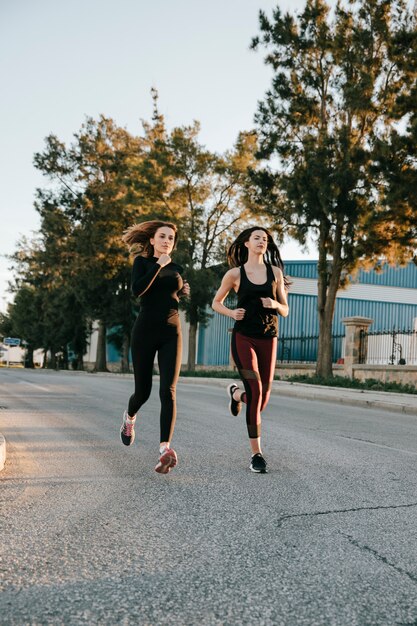 Sportvrouwen die op straat in zonlicht lopen
