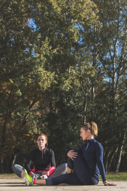 Sportvrouwen doen warm-ups op de grond zitten