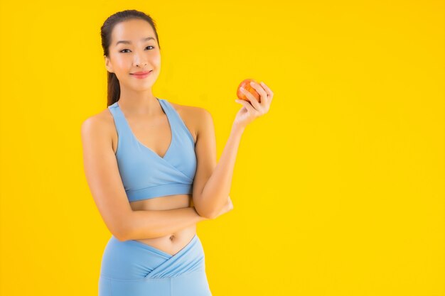 Sportwear van de portret mooie jonge Aziatische vrouw sportwear klaar voor oefening op geel