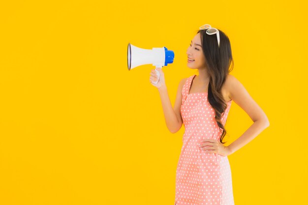 Spreekt de portret mooie jonge Aziatische vrouw luid met megafoon