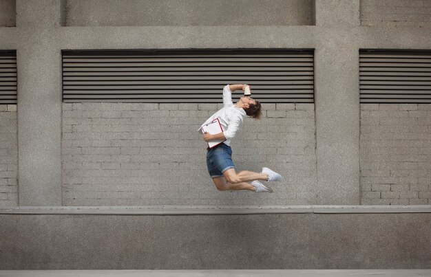 Springende jonge buinessman voor gebouwen, op de vlucht in sprong hoog
