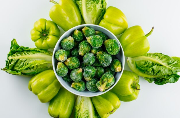 Spruitjes in een kom met sla, paprika's op een witte lijst