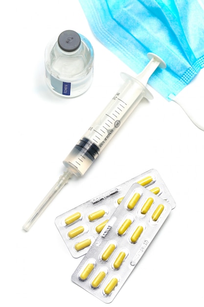 Spuit, capsules en medische masker fles op witte achtergrond