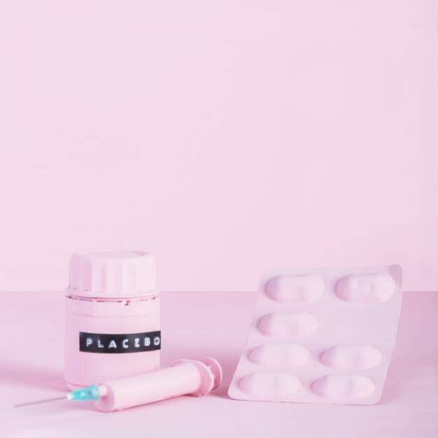Spuit, pillenblaar en placeboxfles op roze achtergrond