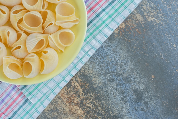 Spuit Rigate pasta in de kom, op de handdoek op de marmeren achtergrond.