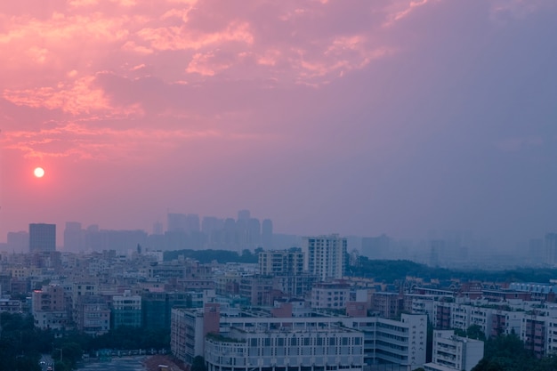 Stad onder een bewolkte hemel tijdens de roze zonsondergang in de avond