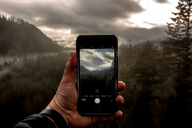 Standpunt van een mannetje dat een smartphone houdt en een foto van een mooi landschap neemt