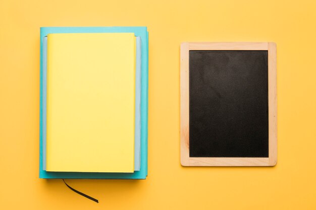 Stapel boeken en schoolbord op gele achtergrond