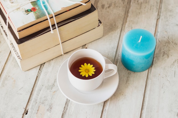 Gratis foto stapel boeken, kaars en koffie met bloem binnen