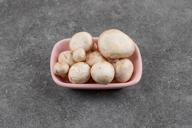 Gratis foto stapel champignons in roze kom over grijs oppervlak