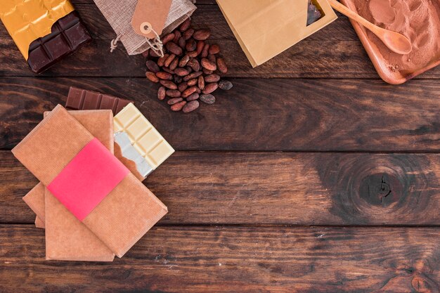 Stapel chocoladerepen, cacaobonen en poeder op houten bureau