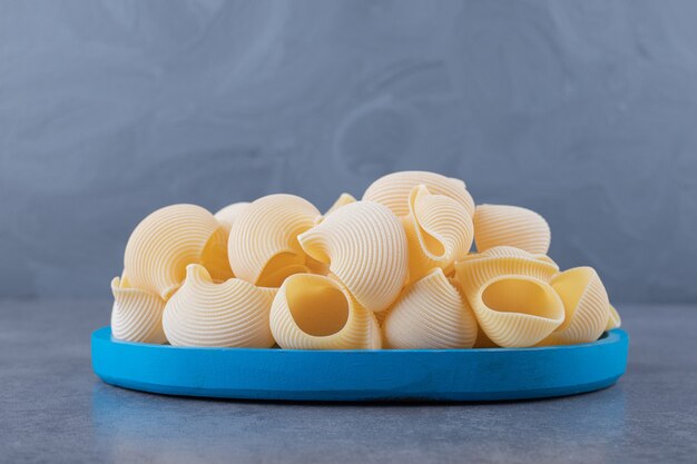 Stapel conchiglie pasta op blauw bord.