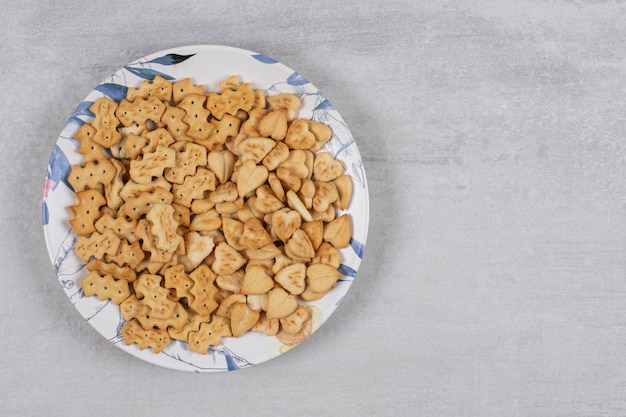 Stapel gezouten crackers op kleurrijke plaat.