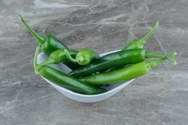 Stapel groene hete pepers in witte kom.