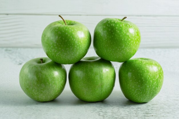 Stapel groene verse appel op grijze ondergrond.