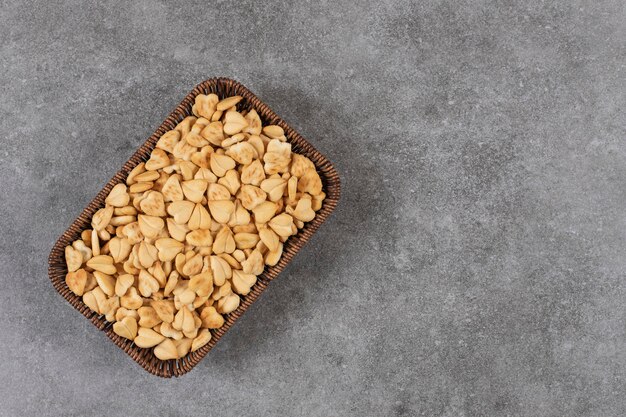 Stapel kleine koekjes in mand over grijze tafel.