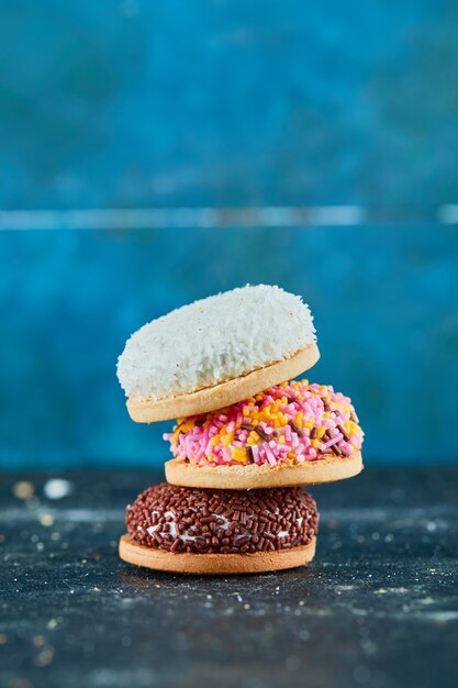 Stapel kleurrijke gezwollen koekjes op blauwe muur.