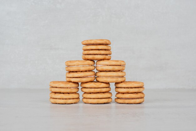 Stapel koekjes met room op witte lijst.