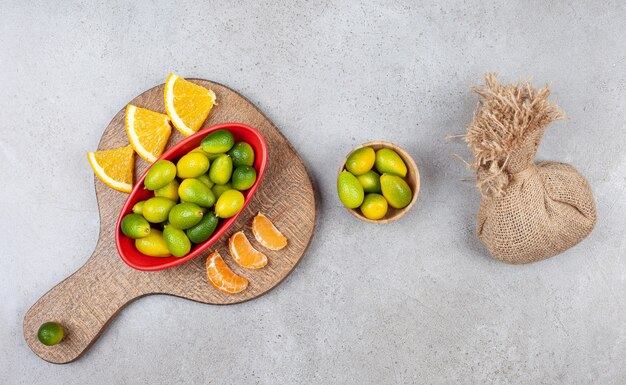 Stapel kumquats met sinaasappel- en mandarijnplakken op een houten bord.