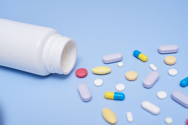 Stapel medische capsules pillen in rode en witte kleur op blauwe ondergrond, bovenaanzicht voor kopie ruimte. Witte medische pillen en tabletten die uit een drugfles morsen. Macro bovenaanzicht met kopie ruimte.