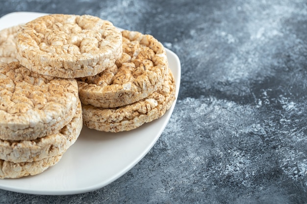 Gratis foto stapel ronde knäckebröd op witte plaat.