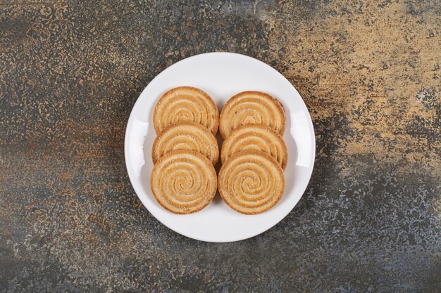Stapel smakelijke ronde koekjes op witte plaat.