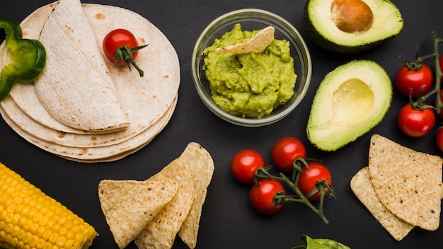 Stapel van pitabroodje dichtbij groenten en saus met nachos