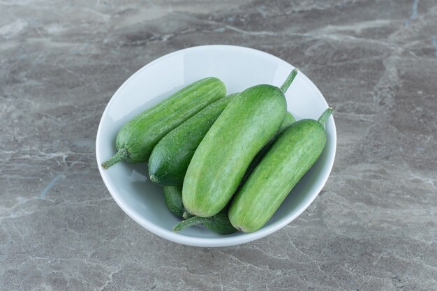 Stapel verse biologische komkommers in witte kom.