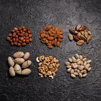 Stapels diverse noten zoals pistache cashew amandel hazelnoot braziliaanse noot en pecannoot