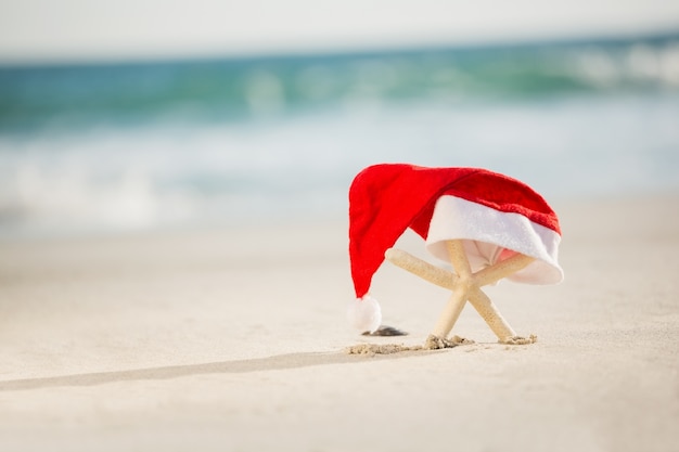 Starfish bedekt met kerstmuts gehouden op zand