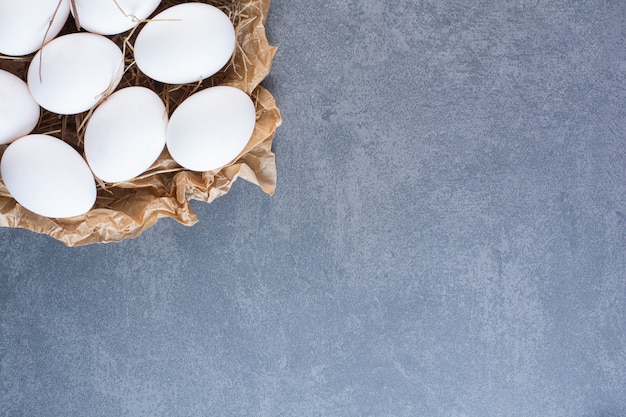 Stelletje rauwe witte eieren op stenen tafel.