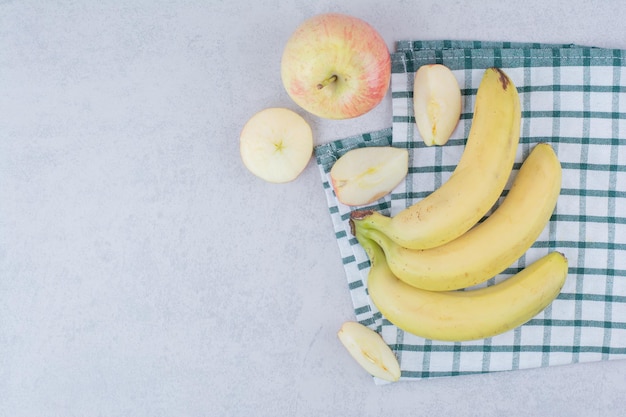 Stelletje rijpe fruitbananen met gesneden appel op tafellaken. Hoge kwaliteit foto